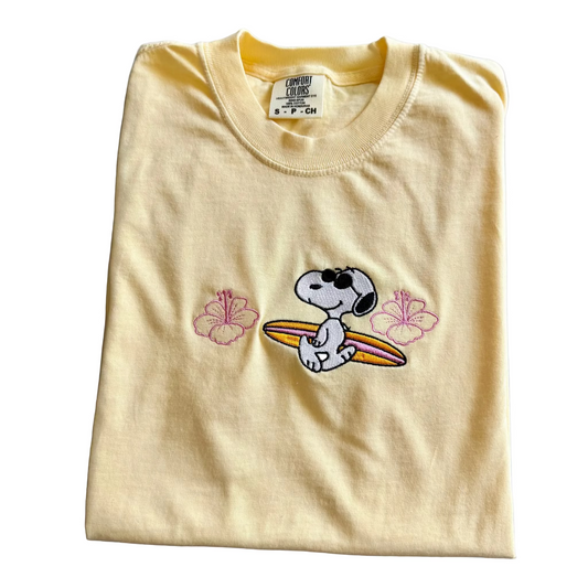 Folded yellow t-shirt with a cartoon character and flowers on a marble surface