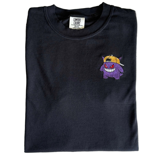Black Comfort Colors T-shirt with purple Gengar wearing a backward yellow hat embroidered on the left chest.